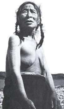 Inuit woman showing tattoo marking on arms, her chin stripes are barely visible - Richard Harrington photo from 1950