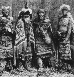 Early photo showing Masset shaman with Haida Chief on right showing tattoos of the Bear on chest and a Whale on his forearm.